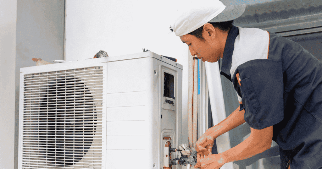 屋外で室外機の配管作業をするエアコン設置スタッフ
