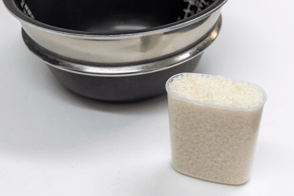計量カップに入れた白米と炊飯器の内釜