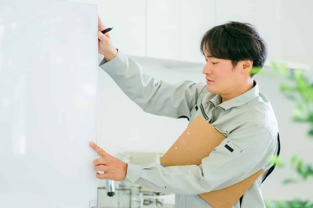 冷蔵庫と作業着姿の男性