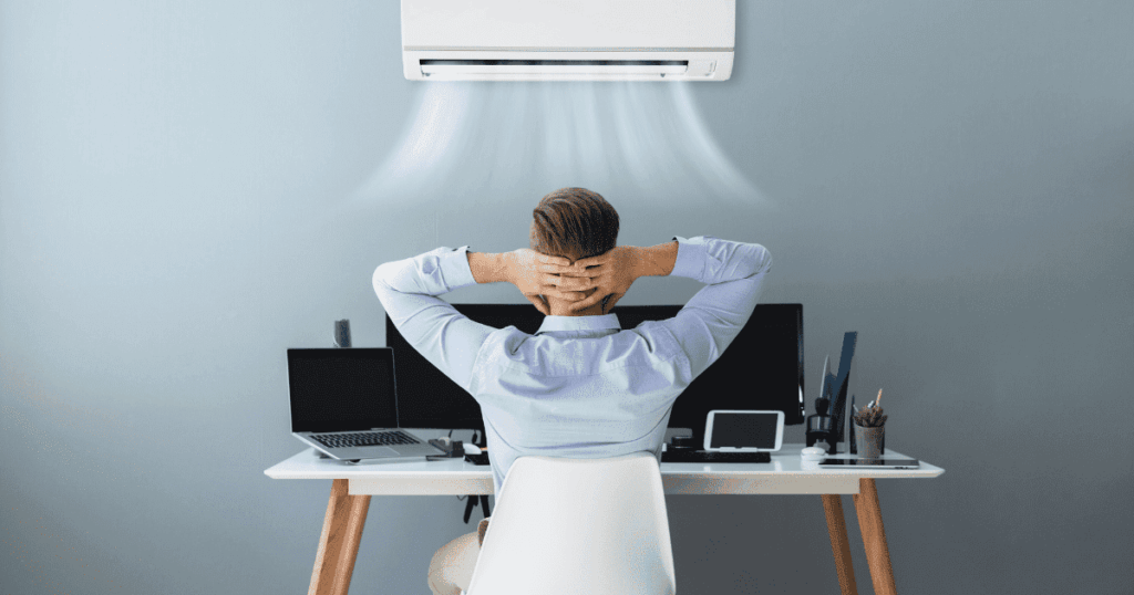デスクワーク中の男性がエアコンの冷風を受けてリラックスしている様子
