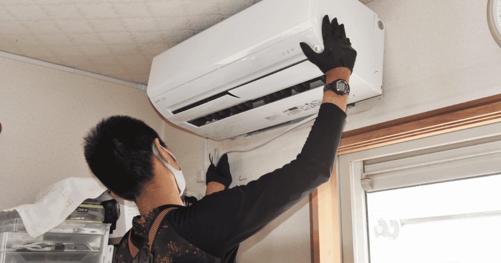 作業員が壁掛けエアコンを設置している施工作業の様子
