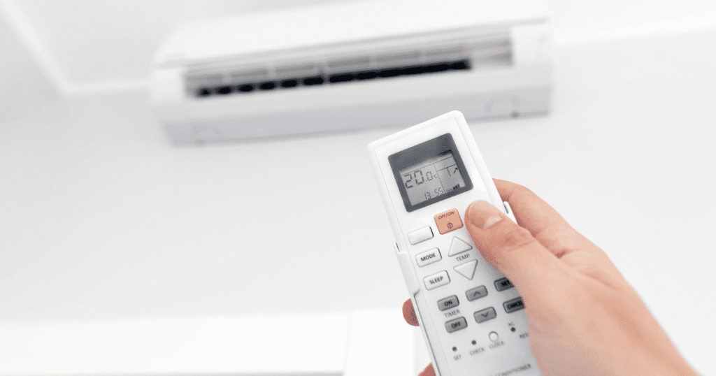 エアコンのリモコンで温度設定を操作している手元の写真