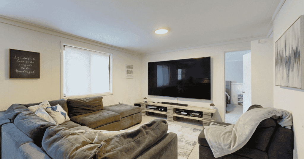 リビングの壁に設置された大型テレビとソファのある空間