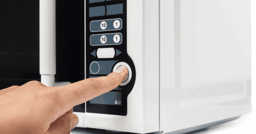 電子レンジのスタートボタンを指で押している手元