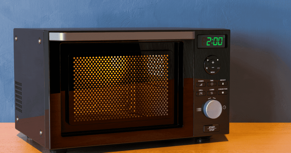 カウンターの上で加熱中の黒い電子レンジとオレンジ色の庫内ランプ