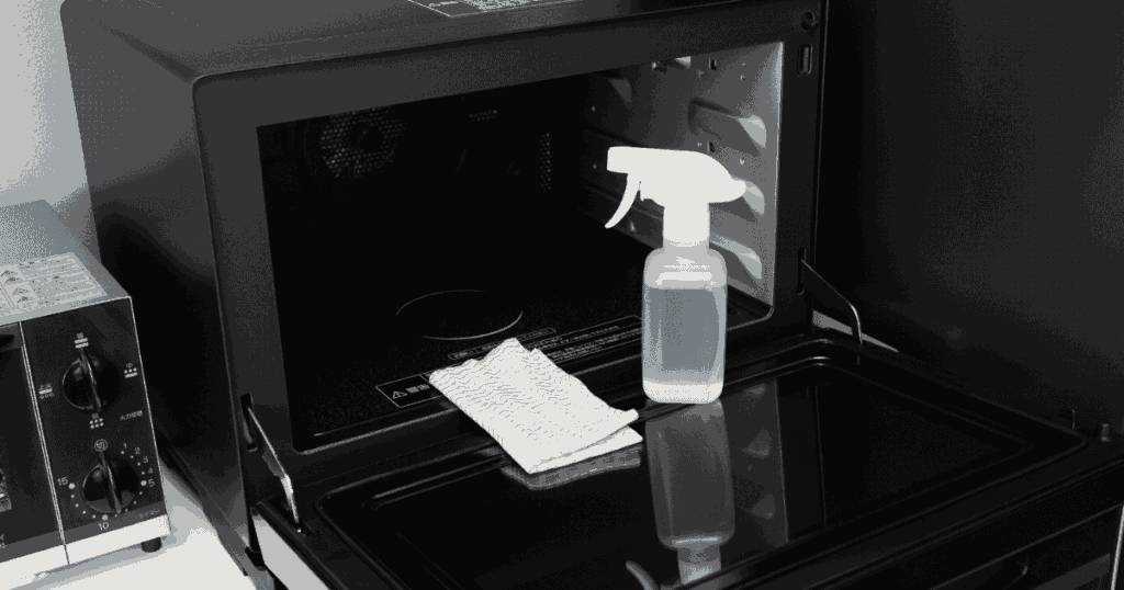 開いた電子レンジと掃除用スプレー、布巾