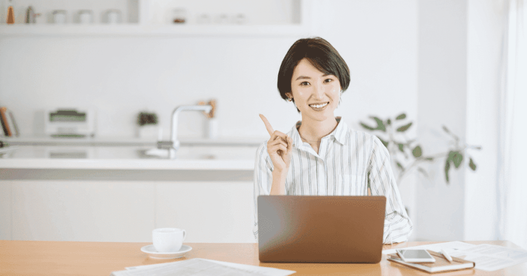 ノートパソコンの前で指を立てる女性