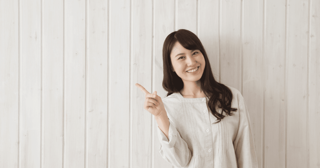 木目の壁の前で指差しをする女性
