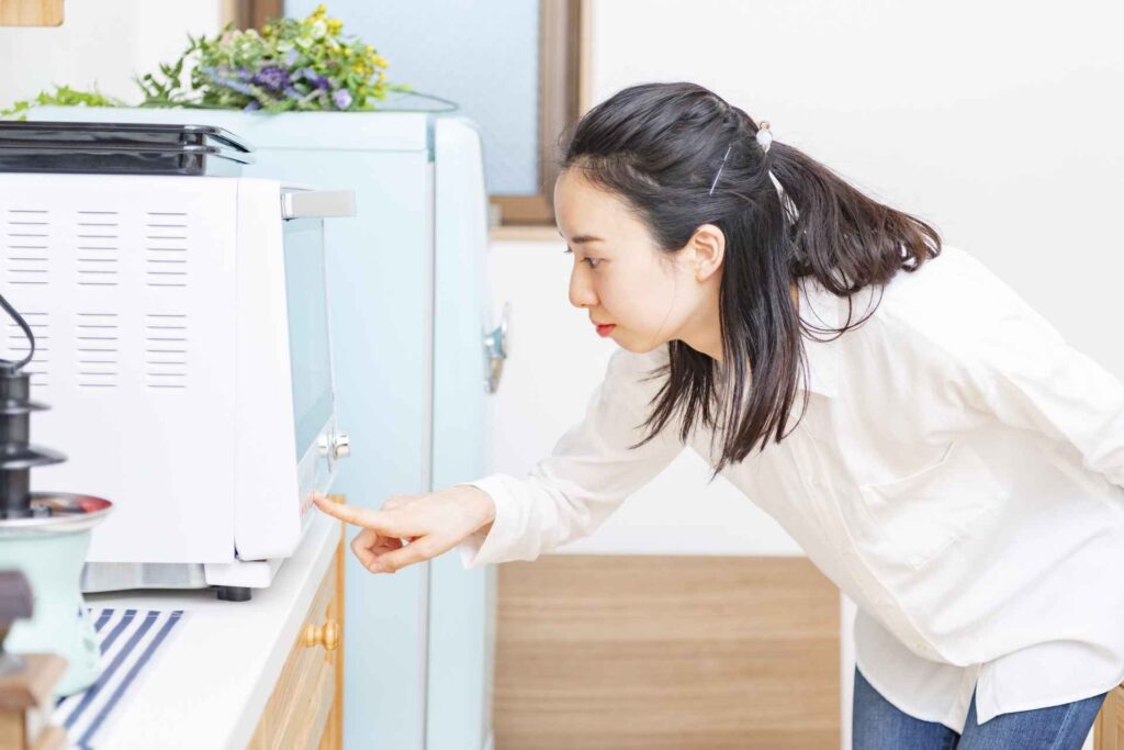 電子レンジを見る女性