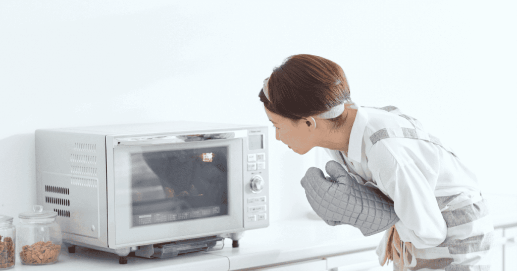 オーブンレンジの庫内をのぞき込みながら焼き上がりを確認する女性