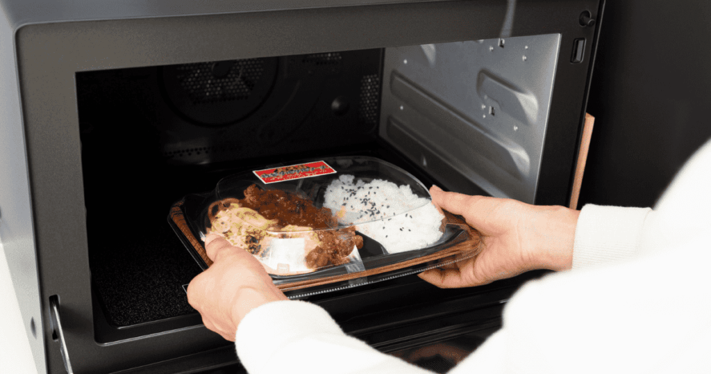 電子レンジに弁当容器を入れる手元