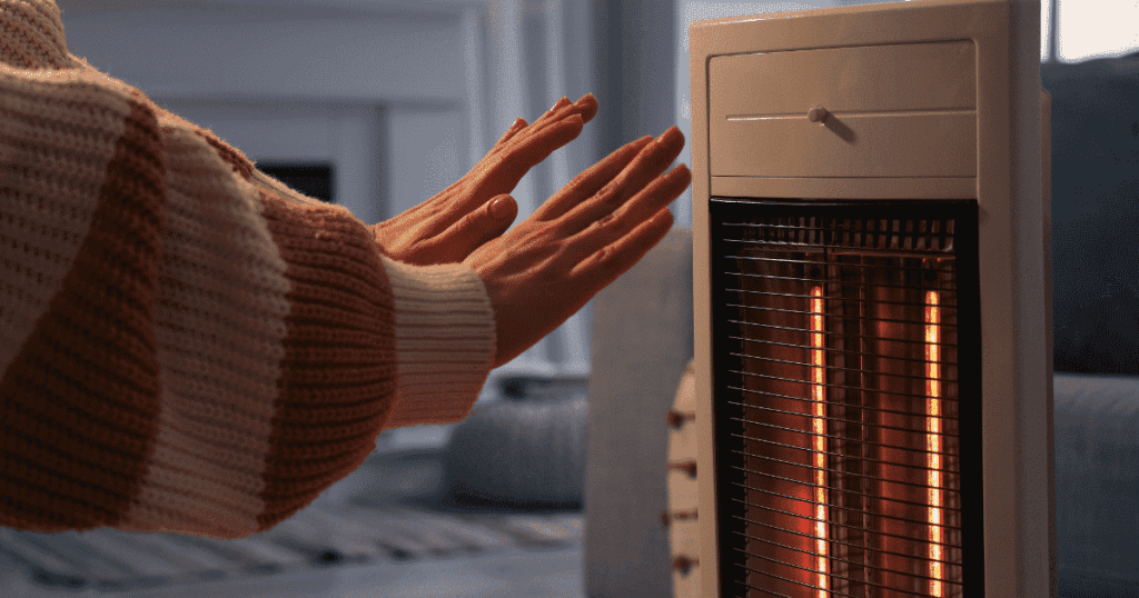 縦型ヒーターの前で手をかざして暖を取る