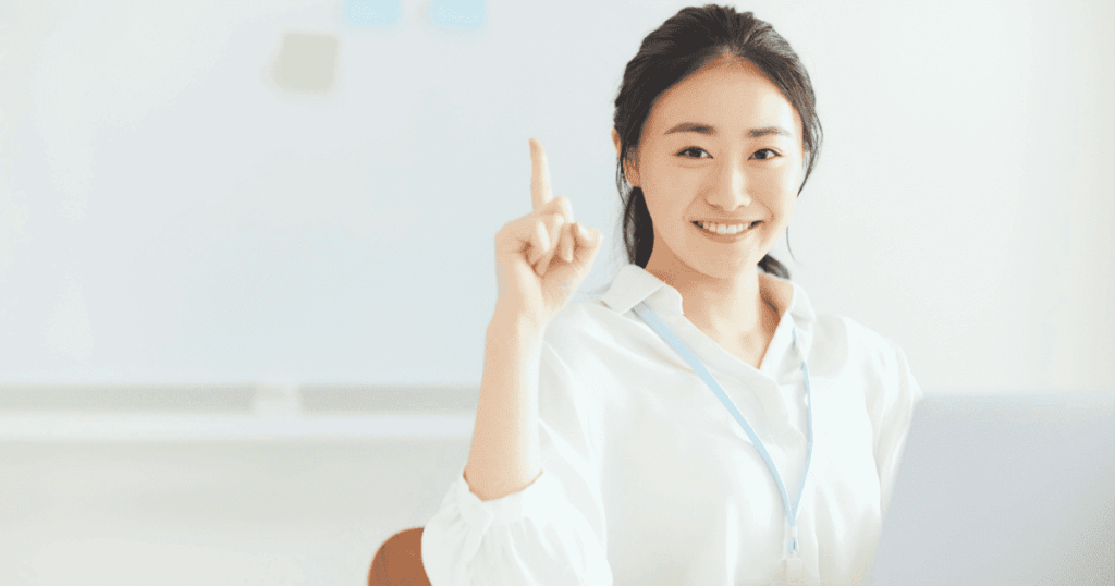笑顔で人差し指を立ててポイントを示す女性