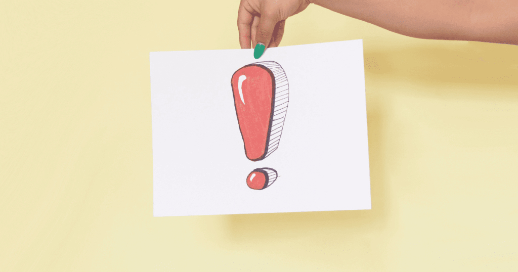 注意を促す赤い感嘆符が描かれた紙を持つ手