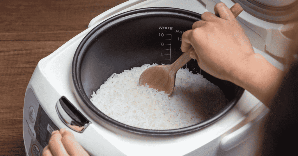 炊飯器の内釜に入ったご飯を木製のしゃもじでほぐす様子
