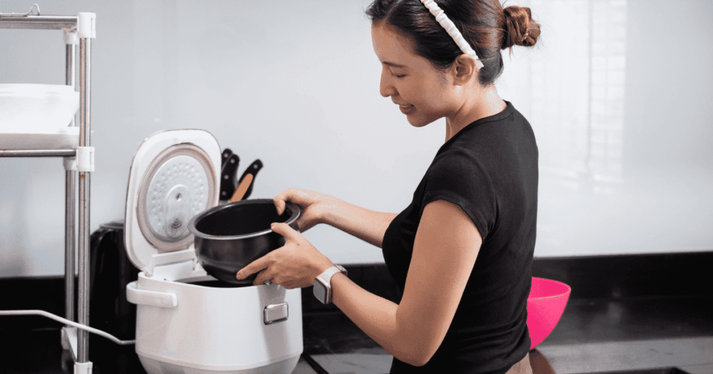 炊飯器の内釜を両手で持つ女性